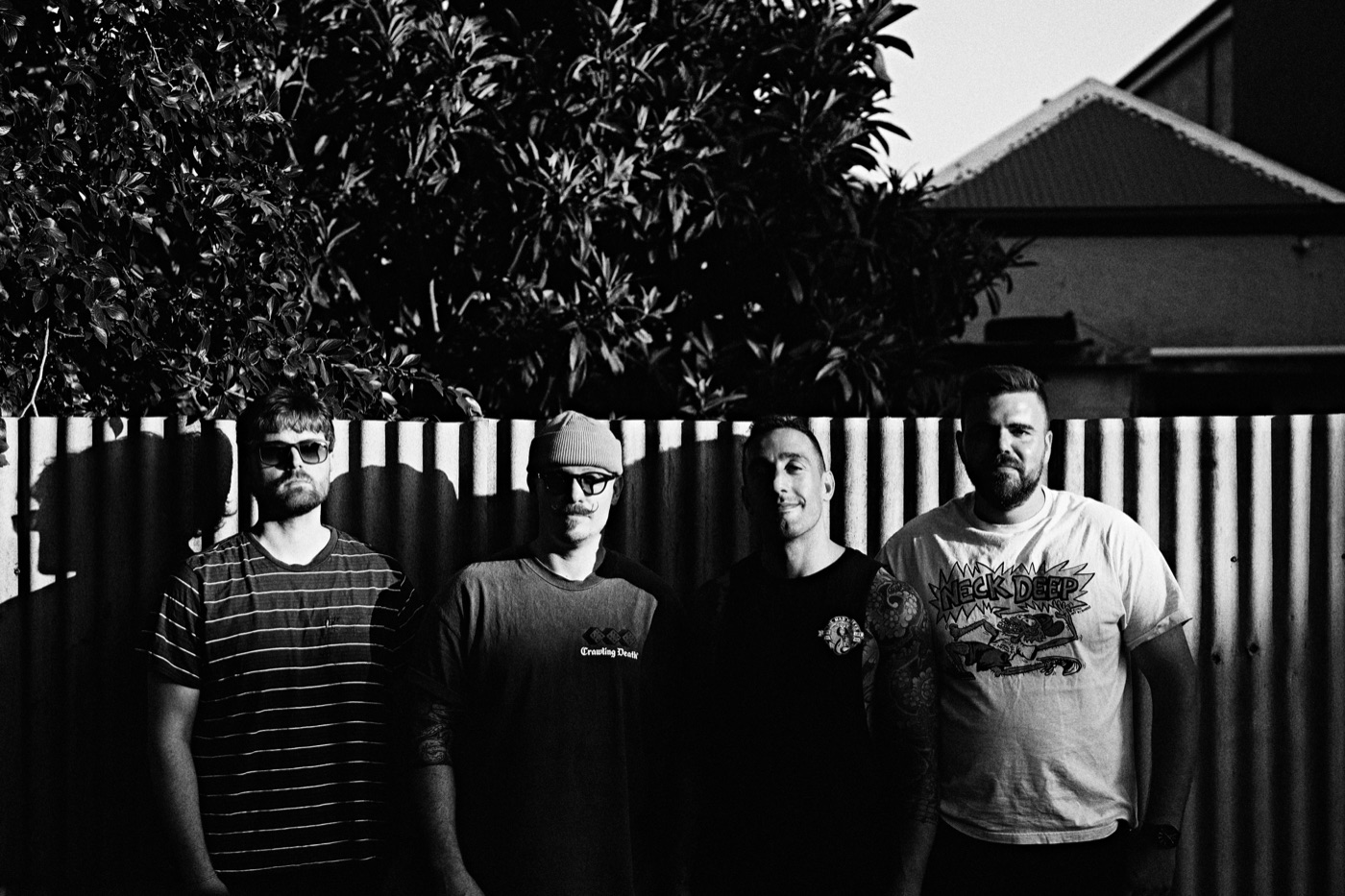 Black and white photo of the band in front of a fence